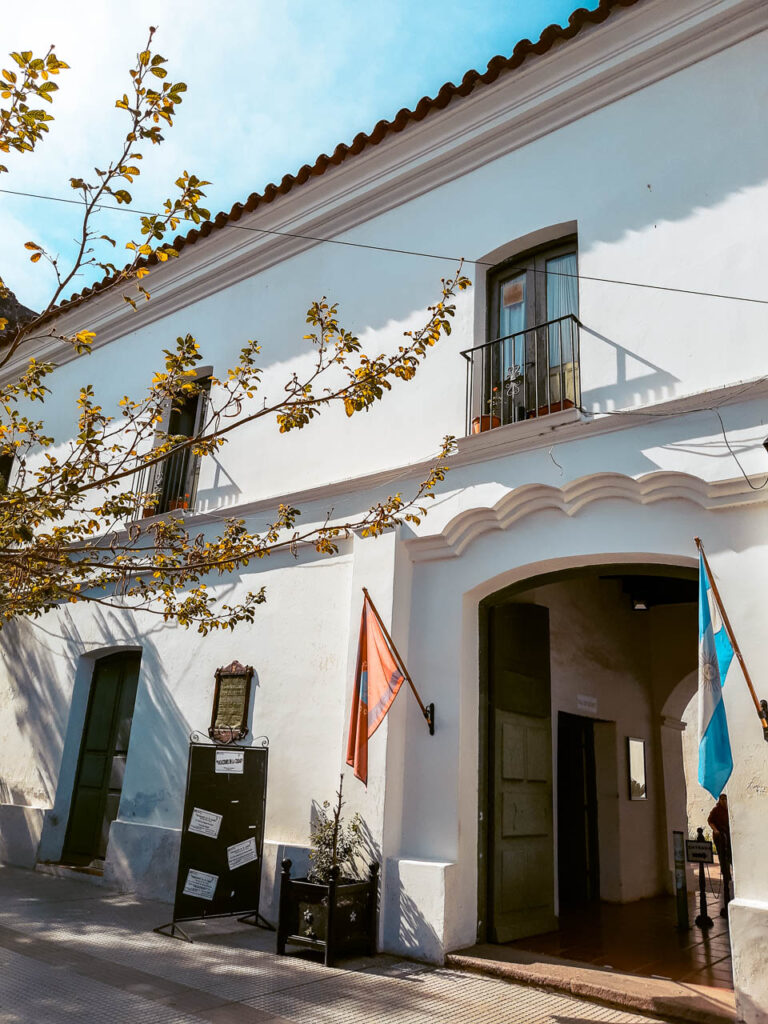 Fachada de la Casa Museo Güemes, de estilo colonial, blanca y con banderas a los lados de la puerta de entrada
