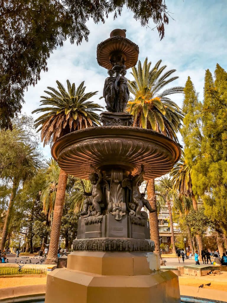 Imagen de la plaza 9 de julio con sus palmeras y una fuente ornamentada con pequeñas esculturas. Sin dudas, un lugar que ver en Salta