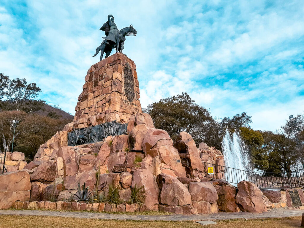 Imponente monumento de 25 metros de alto, realizado con una montaña de piedras extraídas del Cerro San Bernardo en cuya cima se apoya una escultura del General Güemes a caballo