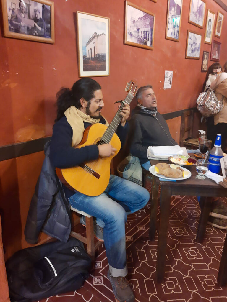Imagen del interior De la Peña La Casona del Molino, con paredes rojizas y dos músicos cantando y tocando la guitarra
